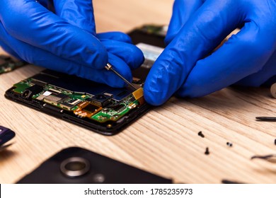 The technician repairing the smartphone's motherboard in the workshop on the table. Concept of computer hardware, mobile phone, electronic, repairing, upgrade and technology.