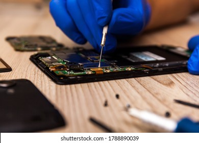 The technician repairing the smartphone's motherboard in the workshop on the table. Concept of computer hardware, mobile phone, electronic, repairing, upgrade and technology.