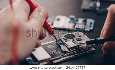 Technician or repairman repairing the smartphone's motherboard in the lab. the concept of phone repair, computer hardware, mobile phone, electronic, repairing