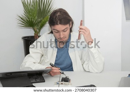 A technician repairs computer equipment using electronic components and tools. Electronics, hardware, workplace. sstkbusiness