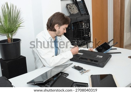 A technician repairs computer equipment using electronic components and tools. Electronics, hardware, workplace. sstkbusiness