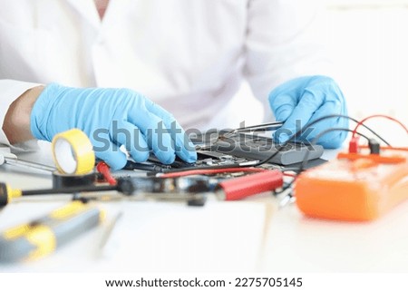 Technician repairs motherboard of smartphone in laboratory