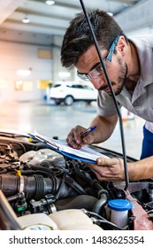 Technician With Safety Glasses Checking The Engine Of A Red Car During A Vehicle Inspection