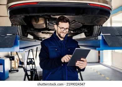 A technician scrolls and smiles at the tablet at mechanic's shop. - Powered by Shutterstock