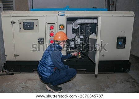A technician sets up backup power. An engineer in a helmet starts a powerful diesel generator.