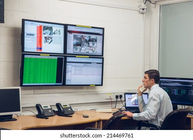 Technician Sitting In Office Running Diagnostics In Large Data Center