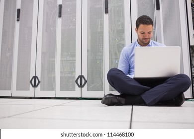 Technician Sitting On Floor Working On Laptop In Data Center