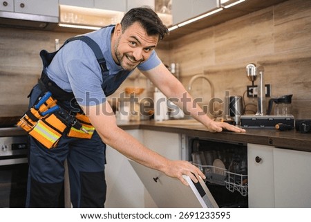 Technician smiling and checking dishwasher in a kitchen