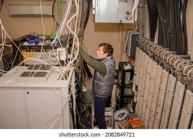 A Technician Is Standing On The Stairs And Laying Wires In The Server Room. Maintenance Of Computer Equipment In The Old Data Center. The Man Works Near The Server Racks.