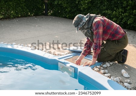 Technician trying to check pool skimmer. Its purpose is to clean the surface by sucking water into a conduit system. It is an essential part of any pool to ensure proper operation and maintenance.