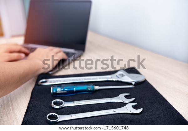 Technician use computer check\
detail of car repair and service  with wrench on black fabric on\
the table