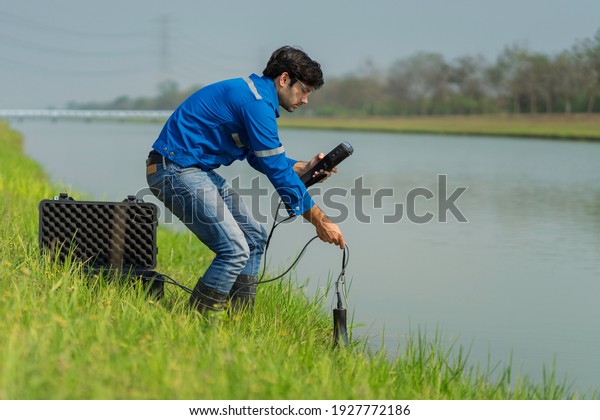 A technician use the Professional Water Testing\
equipment to measure the water quality at the public canal\
,Portable multi parameter water quality measurement ,water quality\
monitoring concept
