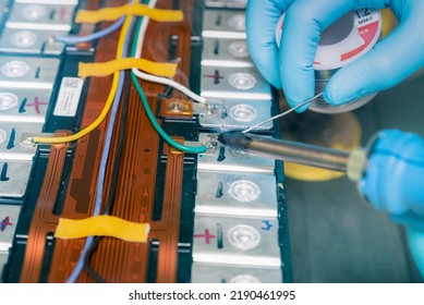 Technician use soldering iron to solder metal and wire of lithium-ion rechargeable battery. Repair module of Li-ion battery. Engineer hand holds soldering iron and tin-lead to solder electronic board.