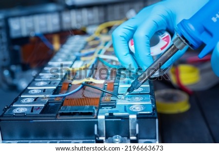 Technician use soldering iron to solder metal and wire of lithium-ion rechargeable battery. Repair module of Li-ion battery. Engineer hand holds soldering iron and tin-lead to solder electronic board. ストックフォト © 
