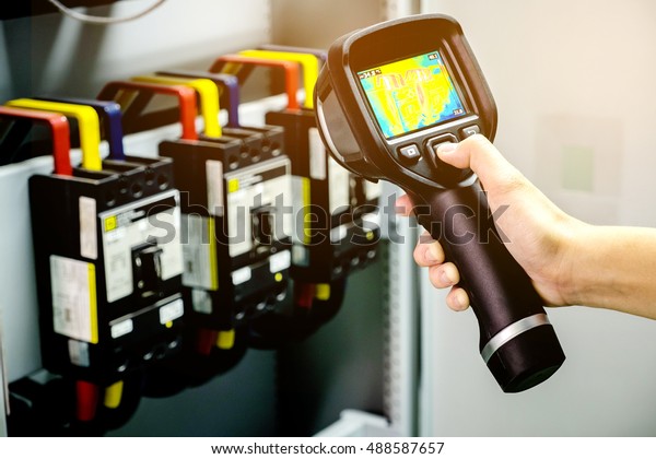 technician use thermal imaging camera to check\
temperature in\
factory