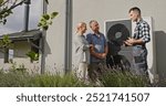 A technician uses a tablet to demonstrate heat pump features to a couple outdoors.