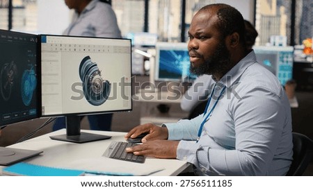 Technician using CAD program on PC to optimize wind turbine design, reducing carbon footprint. RD department employee testing advanced materials for eco friendly windmill components, camera B