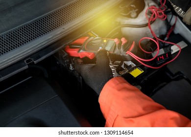 Technician using digital clamp meter to measure and check car battery voltage after changing.
