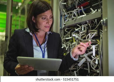 Technician using digital tablet while analyzing server in server room - Powered by Shutterstock - Get 15% off with code: PIKWIZARD15