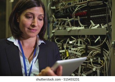 Technician using digital tablet while analyzing server in server room