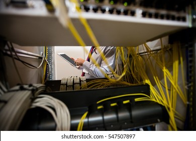 Technician using digital tablet while analyzing server in server room