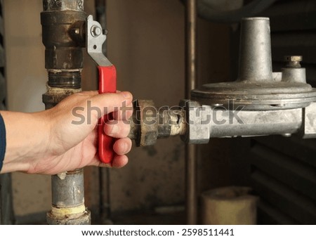 Technician using gas shut-off valve in front of gas pressure regulator. Natural gas boiler supply line for hot water heating. Gas safe, technician or plumbing hot water background. Selective focus.