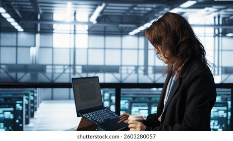 Technician using laptop in data center, finetuning network protocols, holding coffee cup. Woman in server room coding on notebook, enforcing advanced security measures, camera B