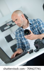 Technician using laptop and holding camera lens