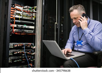 Technician using laptop in server room at the data centre - Powered by Shutterstock