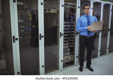 Technician using laptop while analyzing server in server room