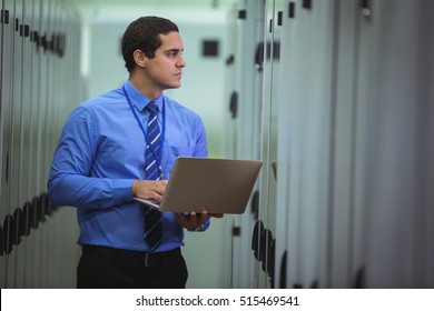 Technician using laptop while analyzing server in server room
