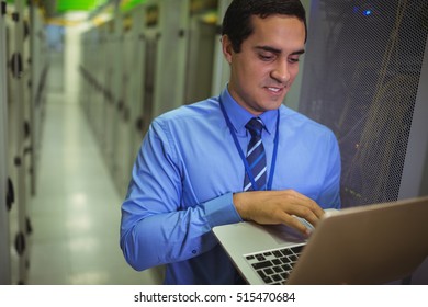 Technician using laptop while analyzing server in server room