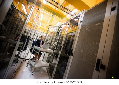 Technician using laptop while analyzing server in server room