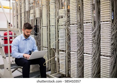 Technician using laptop while analyzing server in server room
