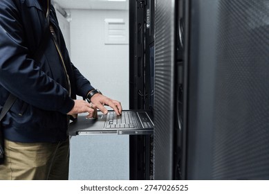 IT technician using rack console laptop to service servers in a data center server room - Powered by Shutterstock - Get 15% off with code: PIKWIZARD15