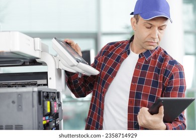 technician using a tablet to fix a printer
