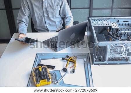 IT technician using tablet and laptop while repairing computer motherboard and computer hardware components.