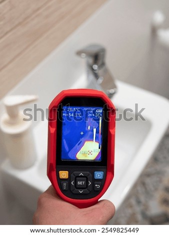 Technician using thermal imaging camera inspecting bathroom sink for heat loss