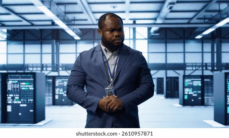 Technician walking between server rows in data center, doing yearly infrastructure inspection. System administrator in server hub monitoring supercomputers equipment, camera A