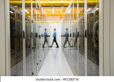 Technician walking in hallway of server room - Shutterstock ID 491330776
