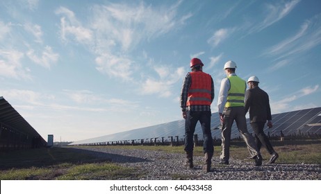 Technician walks with workman and investor through field of solar panels - Shutterstock ID 640433458