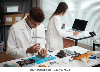 Technician in white lab coat repairing broken smartphone - Powered by Shutterstock