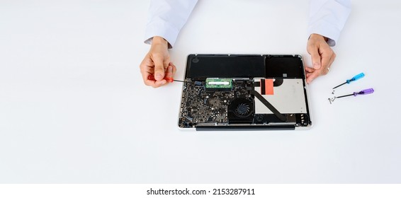 An IT Technician In White Robe Is Repairing A Broken Notebook Laptop Computer Full Of Dust On White Background. Computer Service Concept Copy Space .
