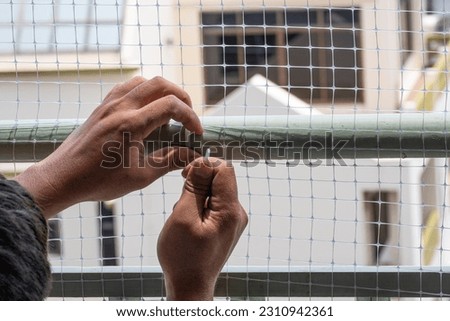 technician worker man install plastic net for protect pigeon bird in balcony apartment by hand use cable ties . Professional service man setup netting birds for clean and hygiene.