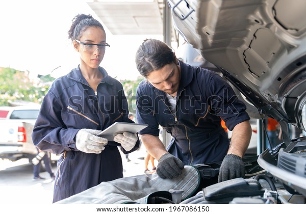 Technician worker\
working and maintenance car engine under hood of car at auto car\
repair service. Group of mechanic vehicle service maintenance under\
car condition in the\
garage