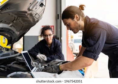 Technician Worker Working And Using Laptop Computer Maintenance Car Engine Under Hood Of Car At Auto Car Repair Service. Group Of Mechanic Vehicle Service Maintenance Under Car Condition In The Garage