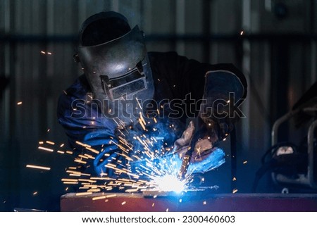 A technician or workers wearing industrial uniforms and welded iron mask at steel welding plants, Industrial safety first concept.
