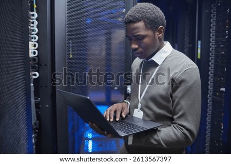 Technician working on configuring server racks inside modern data center, ensuring system functionality and network connectivity