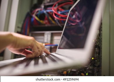 Technician Working On Laptop In Server Room