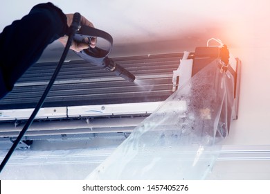 The Technicians Are Cleaning The Air Conditioner By Spraying Water. Hand And Water Spray Are Cleaning The Air Conditioner. Focus At Air Conditioner.